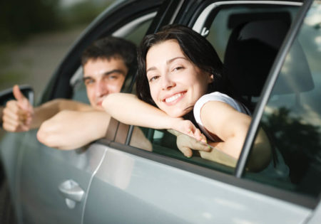 Man and woman in car looking back and smiling