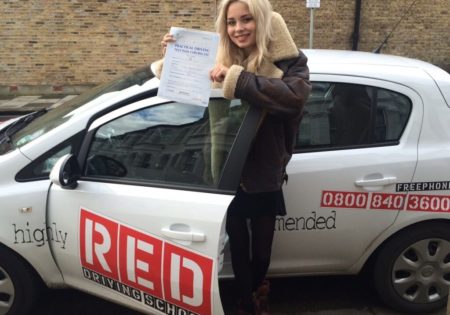 Nina Nesbitt holding driving test certificate infront of white RED car