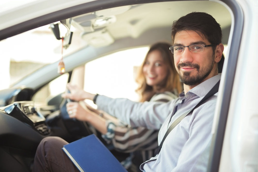 instructor and learner in car smiling at camera