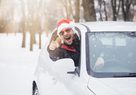 man with santa hat leaning out of car window giving thumbs up