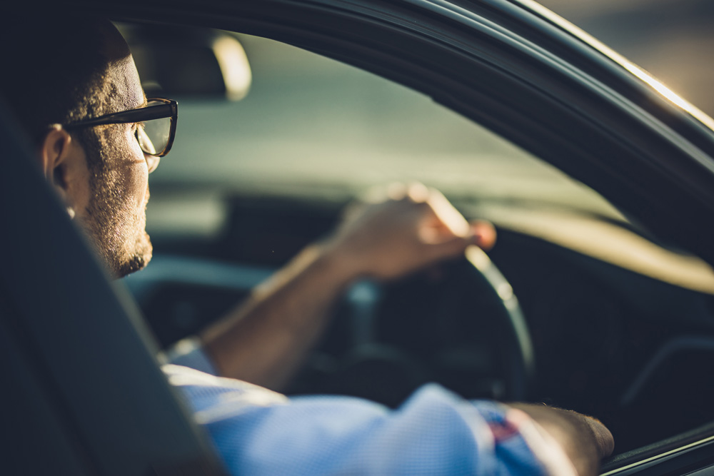 Man with glasses driving car