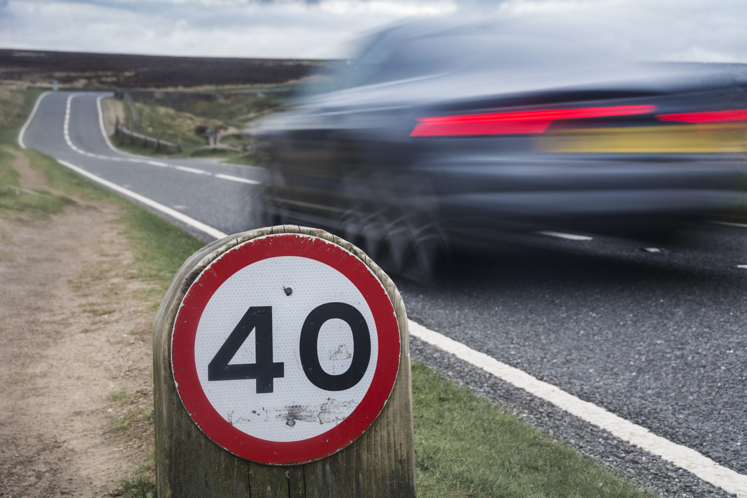 Speed limit sign on rural road with car