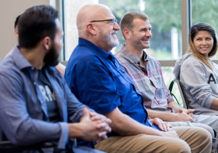 Four people sitting on a chair line, smiling