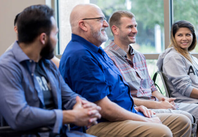 Four people sitting on a chair line, smiling