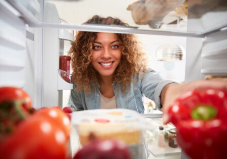 Women open a fridge and picking a pepper